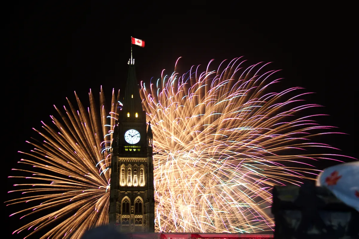 Canada Day fireworks bursting beside the Peace Tower on Parliament Hill in Ottawa at night