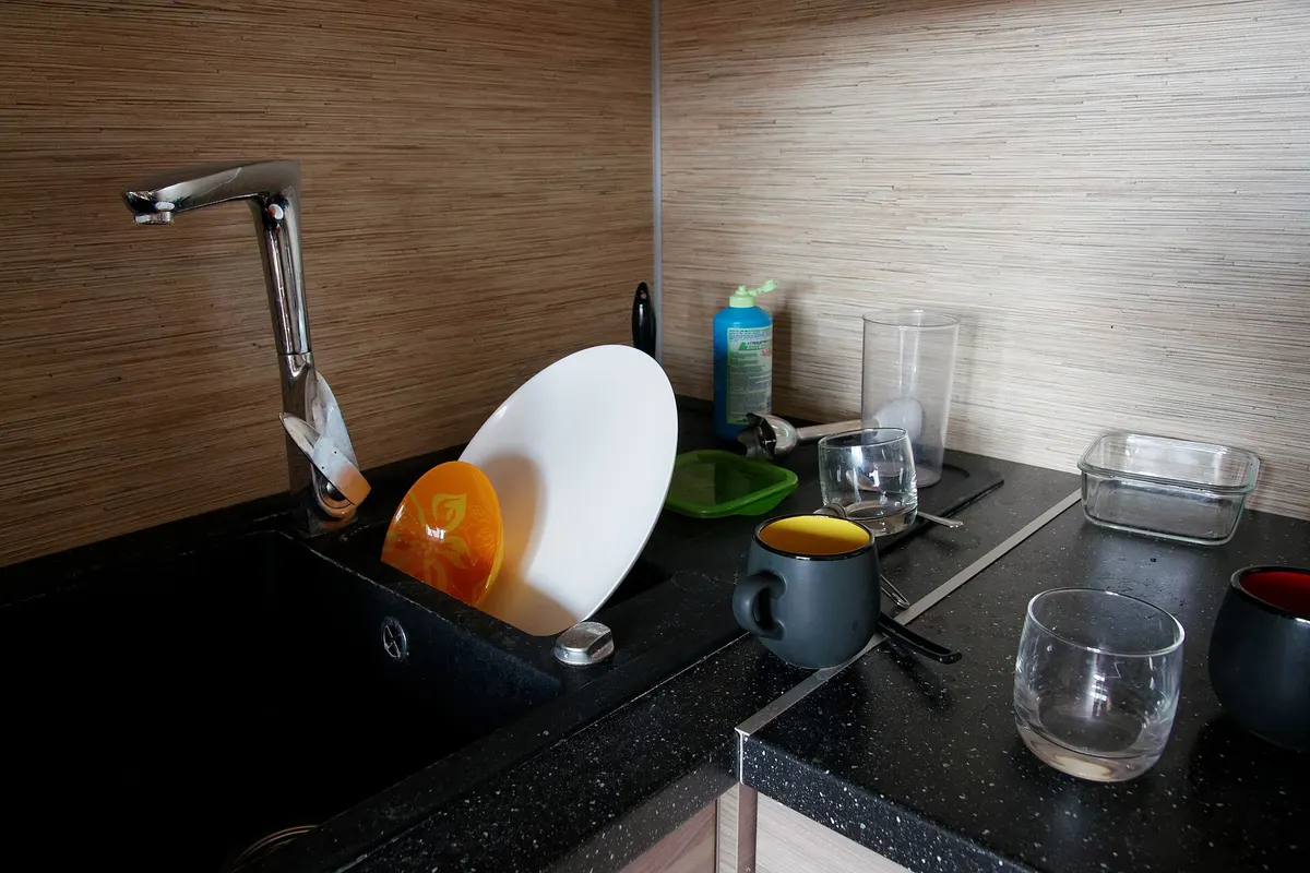 Plates, cups and glasses drying in a dish rack beside a kitchen sink