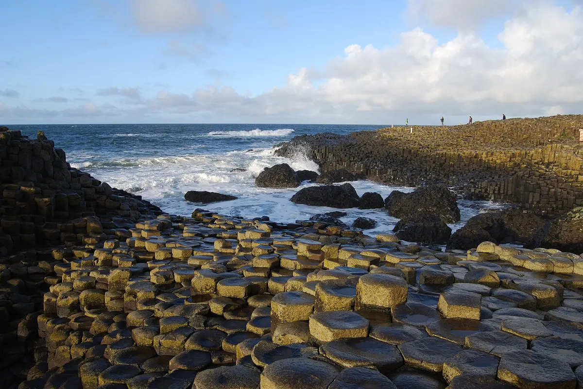 Hexagonal basalt columns of the Giant’s Causeway on the Northern Ireland coast with waves behind