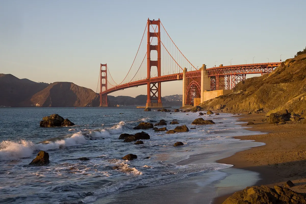 The Golden Gate Bridge in warm evening light seen from a rocky beach in San Francisco