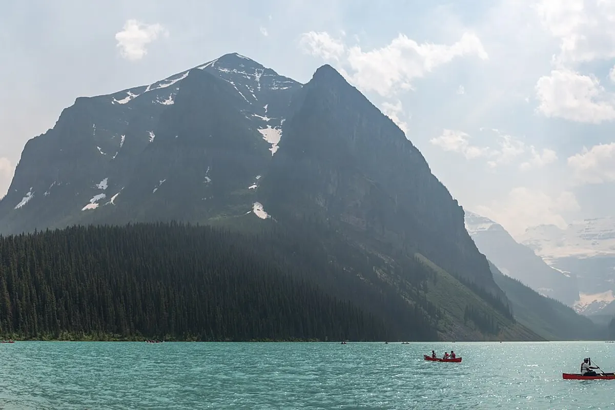 Red canoes on the turquoise water of Lake Louise below snowy mountains in Banff National Park