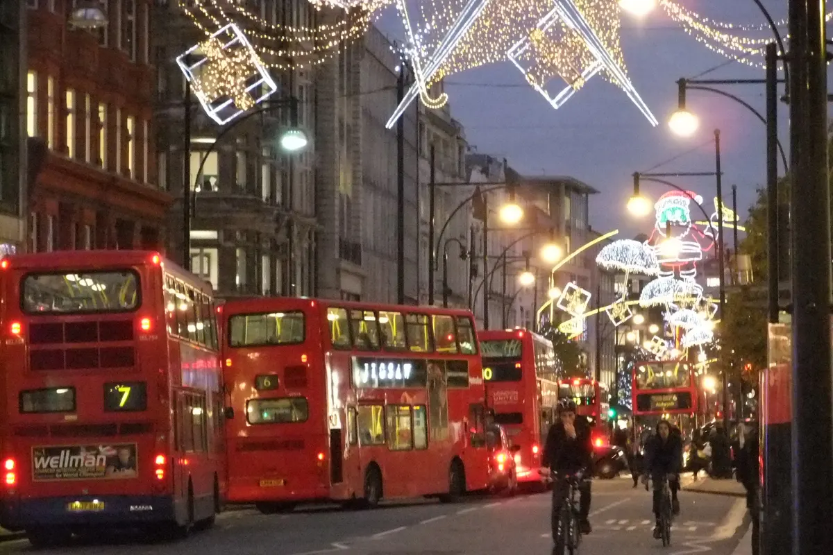 Red double-decker buses on a London street lit with Christmas lights