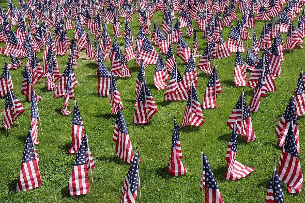 Hundreds of small American flags planted in the grass of a town common for Memorial Day