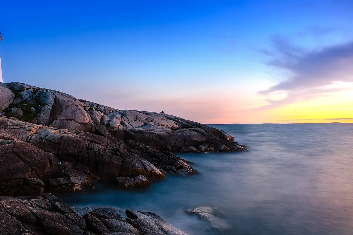 Peggy’s Cove lighthouse on smooth granite rocks above the sea at sunset in Nova Scotia