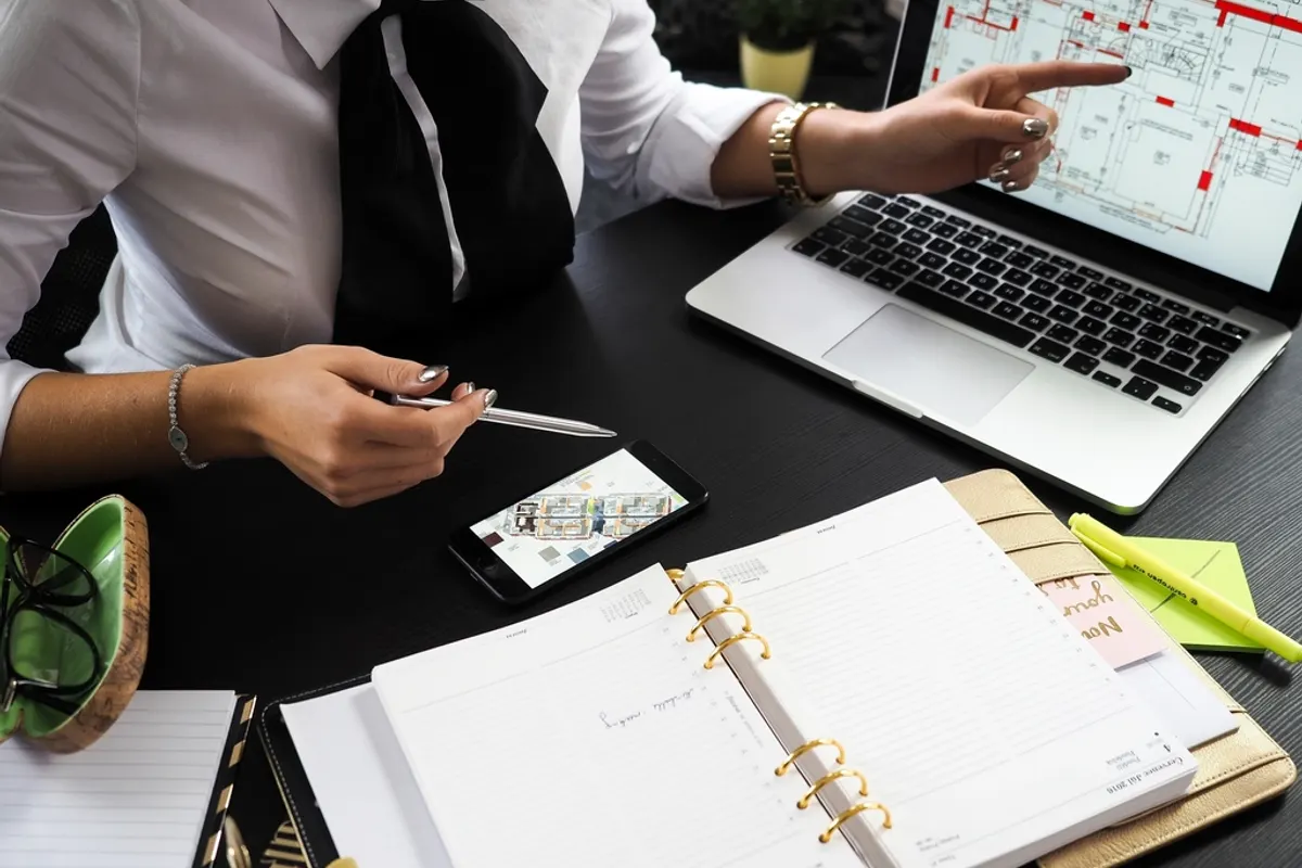 Two people planning work with a ring planner, a phone and a laptop calendar