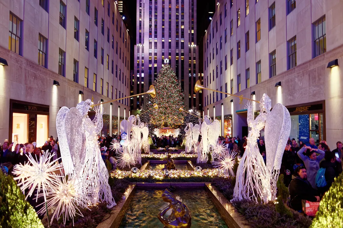 Illuminated angel sculptures leading to the Rockefeller Center Christmas tree in New York at dusk